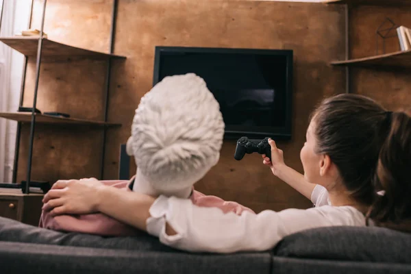 Back view of woman with manikin near by playing video game at home, loneliness concept — Stock Photo