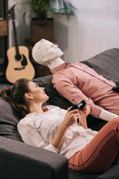 Femme avec mannequin proche en jouant au jeu vidéo à la maison, concept de solitude — Photo de stock