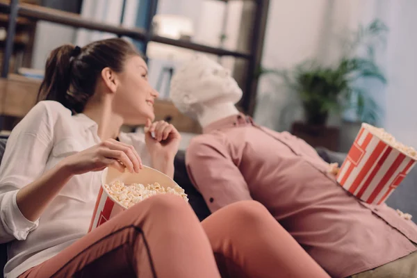 Young woman eating popcorn with manikin near by, one way love concept — Stock Photo