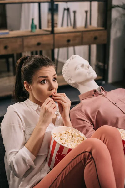 Scared woman eating popcorn while watching film together with manikin at home, perfect relationship dream concept — Stock Photo