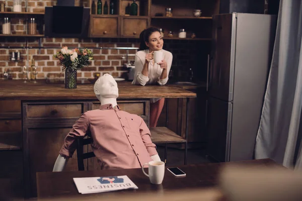 Foyer sélectif de la jeune femme avec tasse de café et mannequin à table dans la cuisine, concept de rêve relation parfaite — Photo de stock