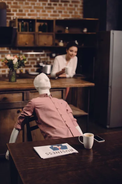 Foyer sélectif de la jeune femme avec tasse de café et mannequin à table dans la cuisine, concept de rêve relation parfaite — Photo de stock