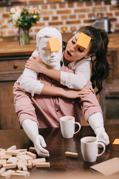 Retrato de mujer con nota adhesiva en la frente abrazando muñeca laico en casa, concepto de sueño relación perfecta - foto de stock