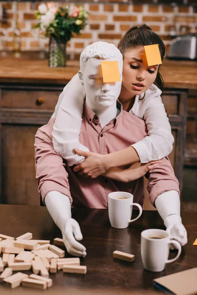 Retrato de mujer joven con nota adhesiva en la frente abrazando muñeca laico, concepto de sueño de relación perfecta - foto de stock