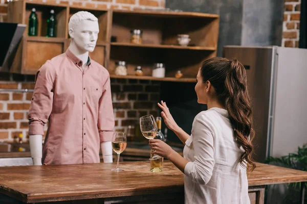 Femme avec verre de vin et mannequin en vêtements décontractés dans la cuisine à la maison, concept d'amour non partagé — Photo de stock