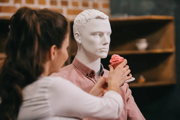 Mulher fingindo alimentar manequim com cupcake em casa, conceito de sonho de relacionamento perfeito — Fotografia de Stock