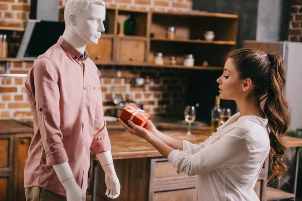 Mujer joven fingiendo excepto regalo de mannikin, la soledad y el concepto de sueño perfecto hombre - foto de stock