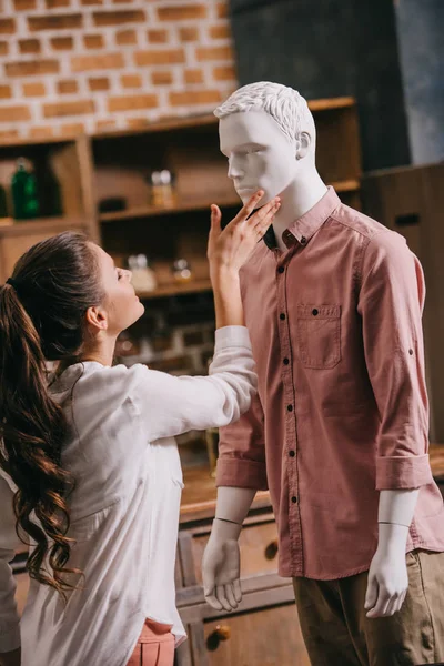 Vista lateral de la mujer tocando maniquí en ropa casual, concepto de amor unidireccional - foto de stock