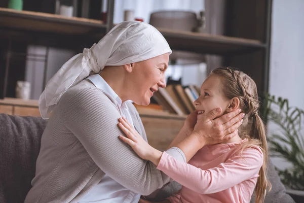 Side view of sick grandmother and cute little granddaughter smiling each other — Stock Photo