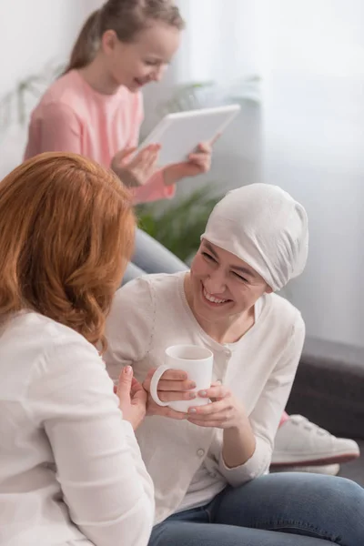 Smiling women drinking tea and child using digital tablet, cancer concept — Stock Photo