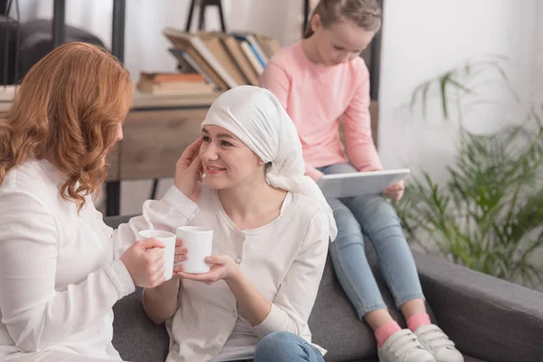 Women drinking tea and child using digital tablet, cancer concept — Stock Photo