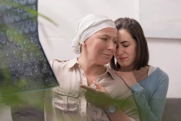 Upset crying woman supporting sick mature mother holding mri scan — Stock Photo