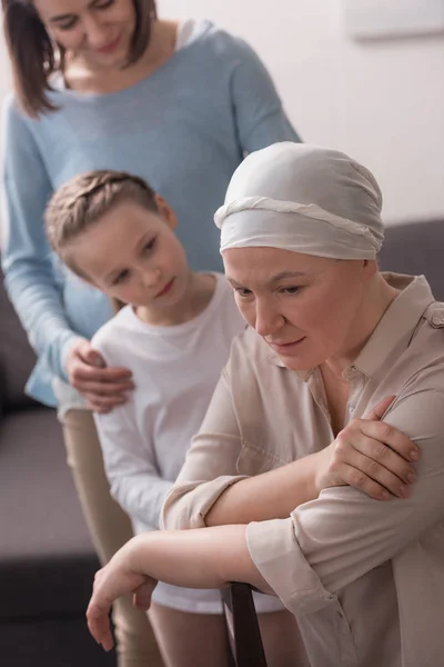 Family supporting mature sick woman in kerchief — Stock Photo