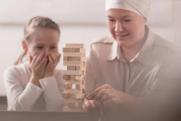 Kind mit kranker Großmutter in Halstuch spielt gemeinsam mit Holzklötzen — Stockfoto