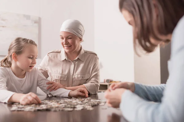 Familia feliz jugando con rompecabezas juntos, concepto de cáncer - foto de stock