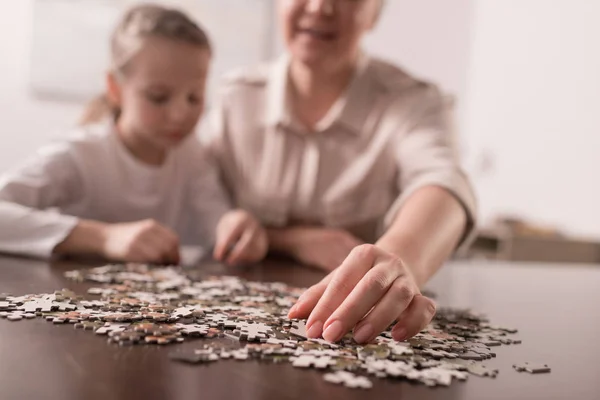 Close-up view of grandmother and granddaughter playing with jigsaw puzzle together, cancer concept — Stock Photo