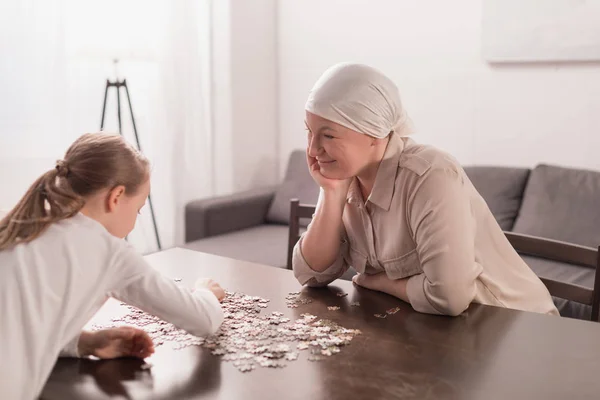 Mignon petit enfant avec grand-mère malade dans le mouchoir jouer avec puzzle ensemble — Photo de stock