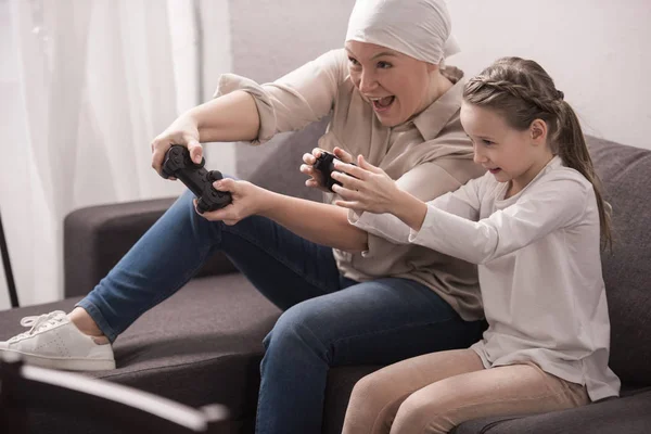Excité grand-mère et petite-fille jouer avec joysticks, concept de cancer — Photo de stock