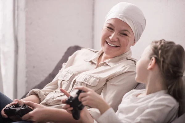Happy grandmother and granddaughter playing with joysticks, cancer concept — Stock Photo