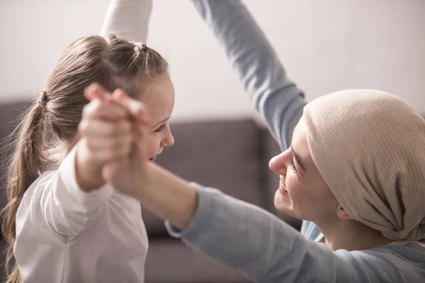 Niño feliz y madre enferma en pañuelo tomados de la mano y sonriendo el uno al otro - foto de stock
