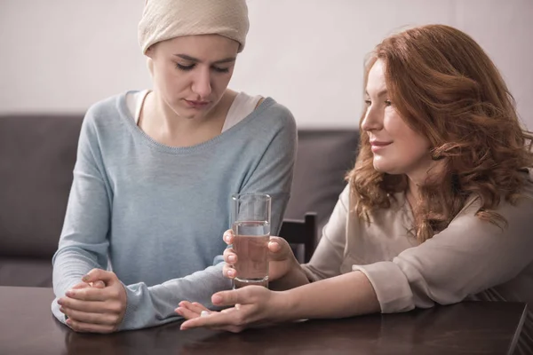 Upset sick woman looking at mature mother holding glass of water — Stock Photo