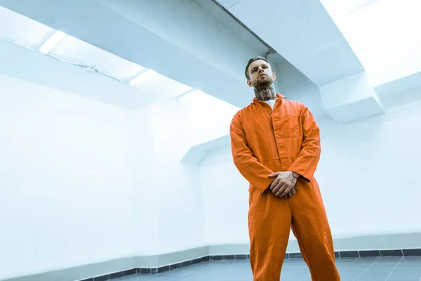 Bottom view of tattooed criminal standing in prison cell — Stock Photo