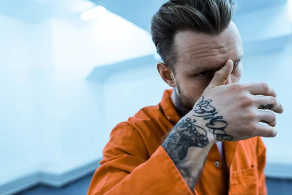 Prisonnier tatoué couvrant le visage avec la main — Photo de stock