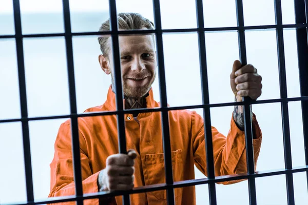 Prisionero sonriente sosteniendo barras de prisión - foto de stock