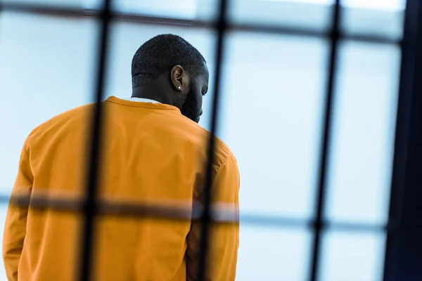 Back view of african american prisoner behind prison bars — Stock Photo