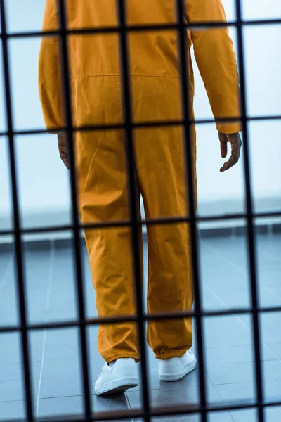 Cropped image of african american prisoner behind prison bars — Stock Photo