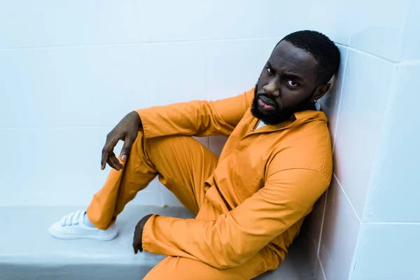 African american prisoner sitting on bench and looking at camera — Stock Photo