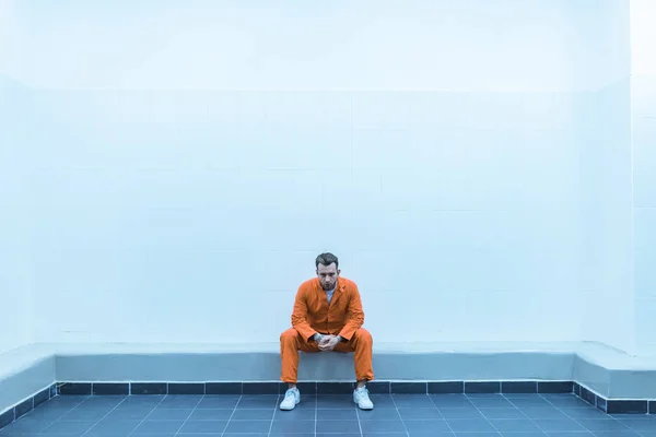 Prisoner sitting on bench in prison room — Stock Photo