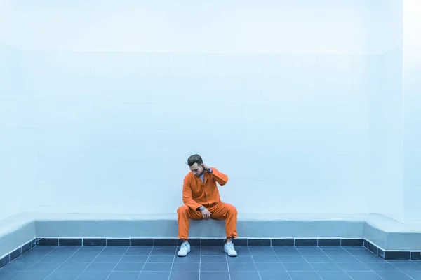 Prisionero sentado en el banco en la celda de la prisión - foto de stock