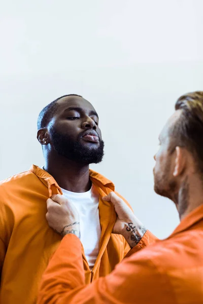 Prisionero amenazando a compañero de celda afroamericano aislado en blanco - foto de stock