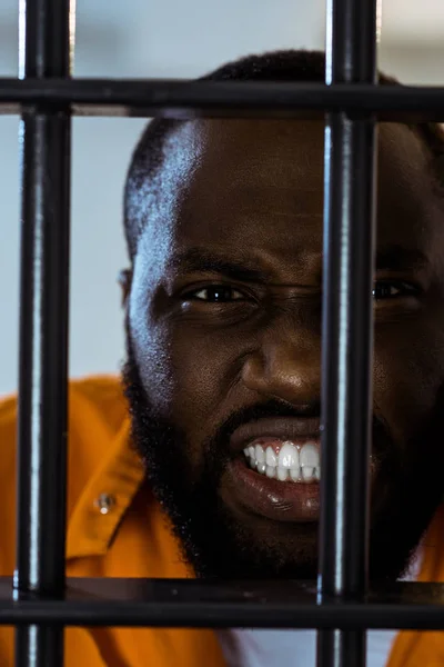 Aggressive african american prisoner behind prison bars — Stock Photo