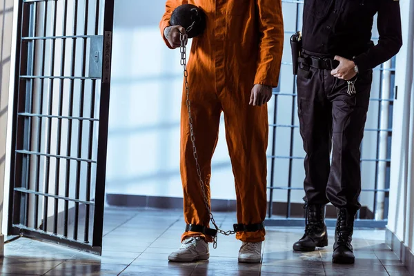 Cropped image of prison officer leading prisoner carrying weight tethered to leg — Stock Photo