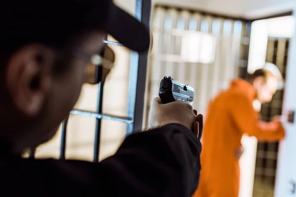 Prison officer aiming gun at escaping prisoner — Stock Photo