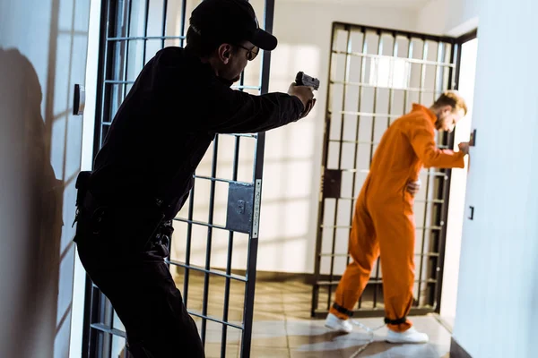 Guardia de la prisión apuntando arma a escapar prisionero - foto de stock