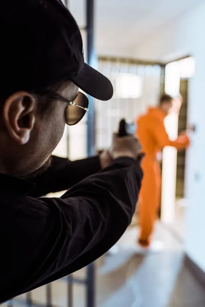 Prison guard aiming gun at prisoner — Stock Photo