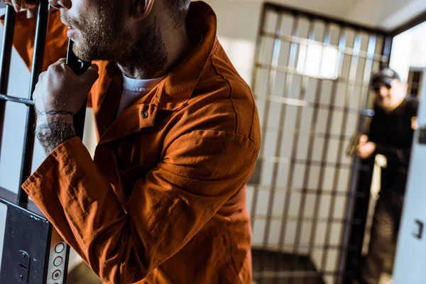 Cropped image of prisoner leaning on prison bars — Stock Photo