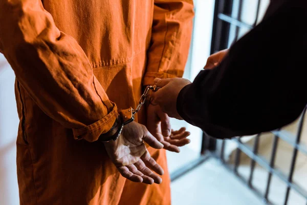 Cropped image of prison officer wearing handcuffs on prisoner — Stock Photo