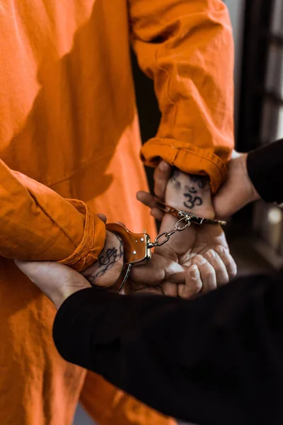 Imagen recortada del oficial de la prisión que tiene convicto esposado - foto de stock