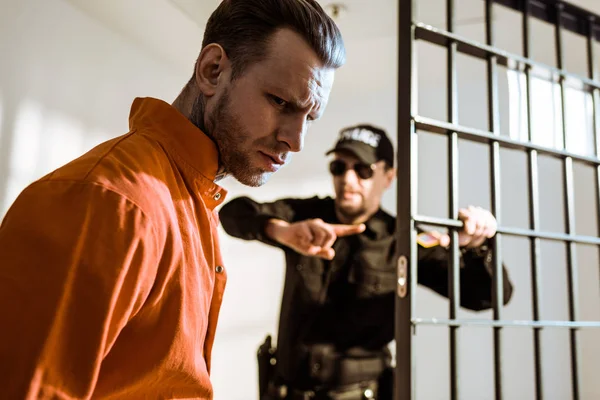Тюремный охранник показывает что-то преступнику в камере — стоковое фото