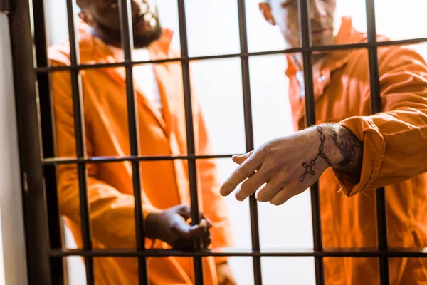 Multikulturelle Häftlinge stehen in Gefängniszellen in der Nähe von Gittern — Stockfoto