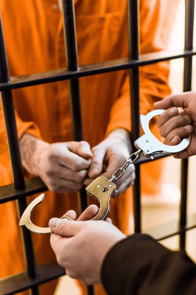 Cropped image of prison warden wearing handcuffs on prisoner — Stock Photo