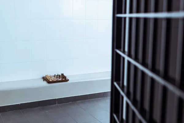 Leere Gefängniszelle mit Schachbrett auf Bank — Stockfoto