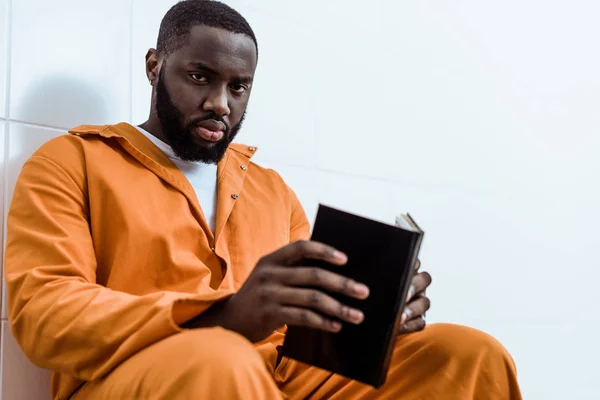 Prisioneiro afro-americano segurando livro e olhando para a câmera — Fotografia de Stock