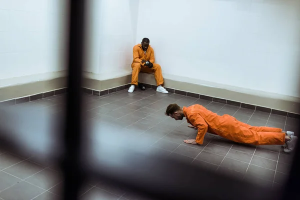 Prisoner doing push-ups on floor in prison cell — Stock Photo