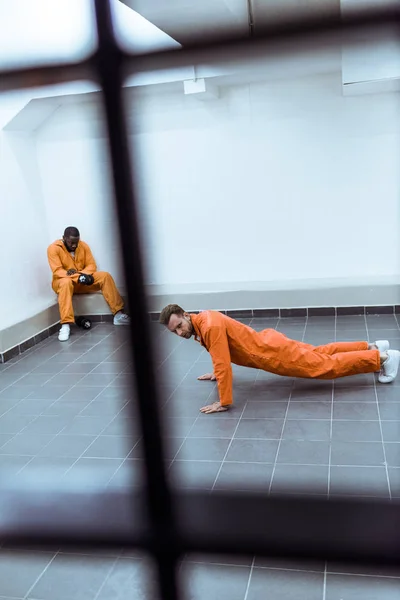 Prisoner doing push-ups in prison cell — Stock Photo