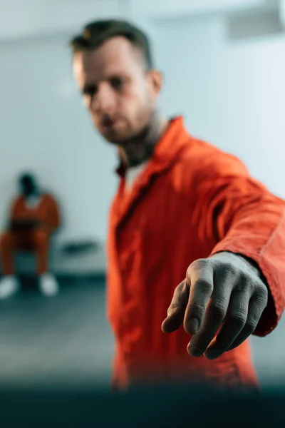 Prisioneiros multiétnicos na cela de prisão com a mão em primeiro plano — Fotografia de Stock